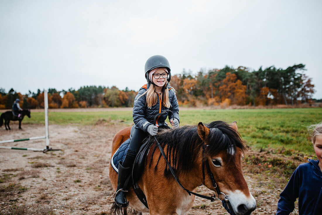 Smiling girl riding pony