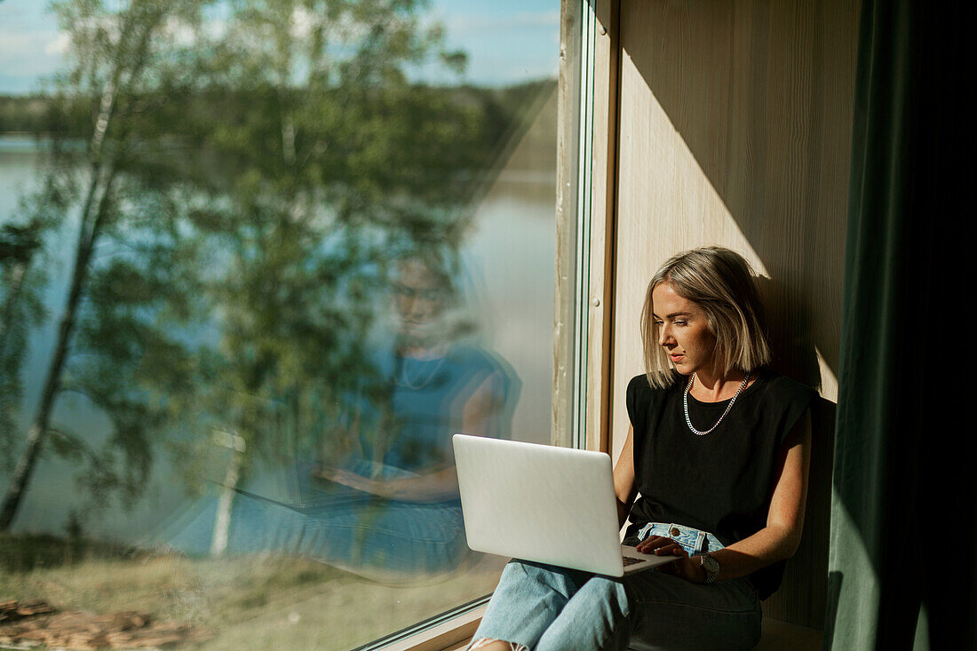 Woman using laptop near window