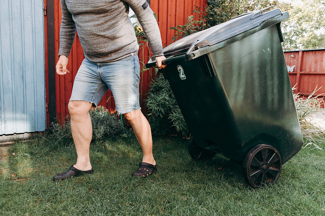 Mann beim Ziehen einer Mülltonne