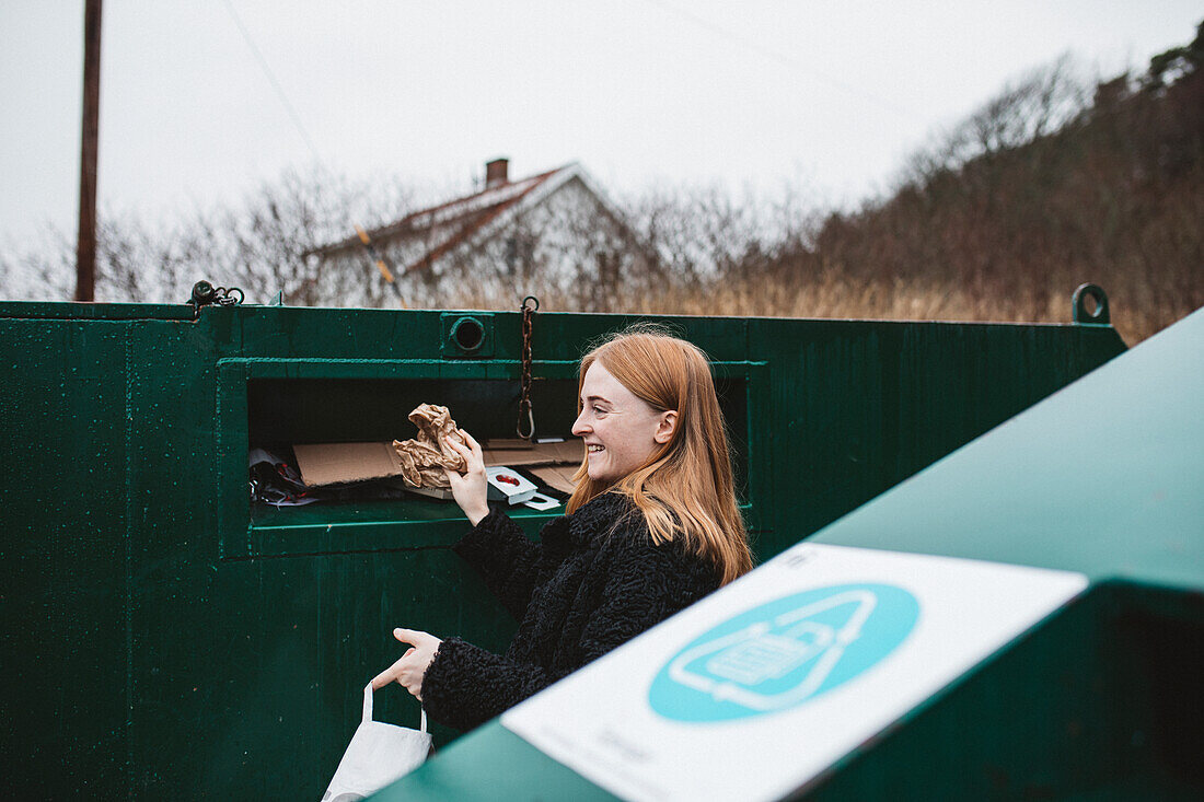 Frau wirft Müll in die Recycling-Tonne