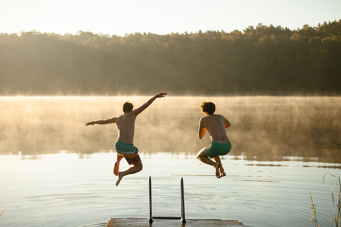 Young men jumping into lake
