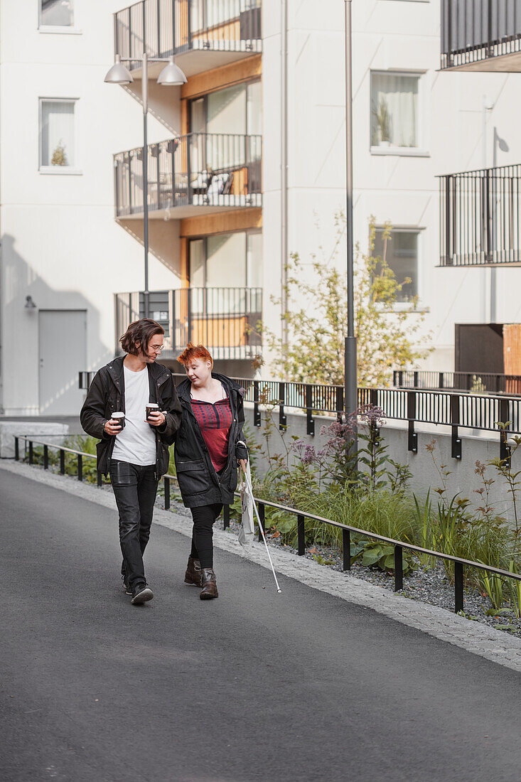 Visually impaired woman walking in street with male friend