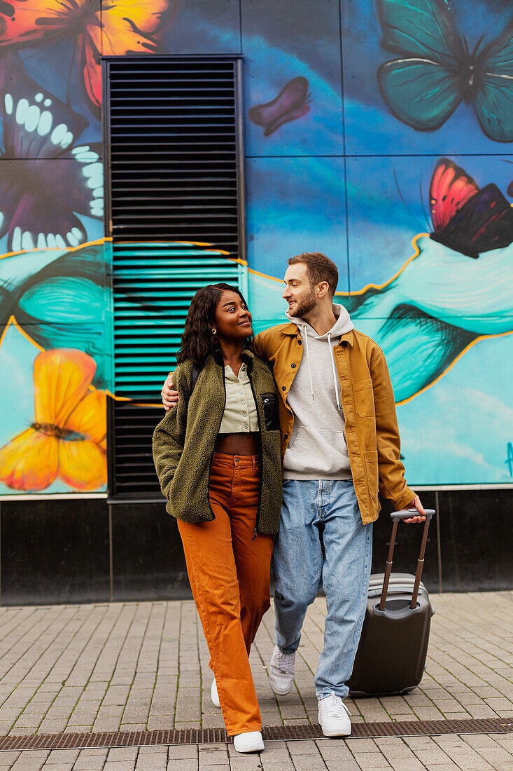 Young couple walking on street with luggage