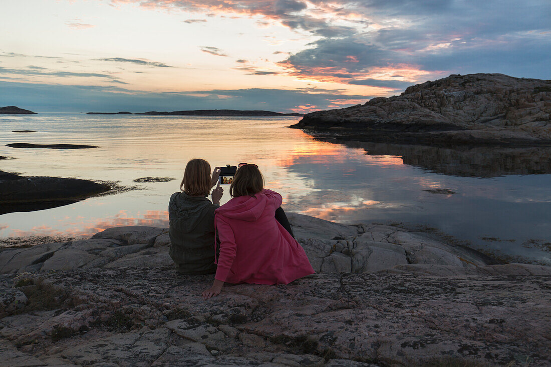 Woman at sea taking picture of sunset