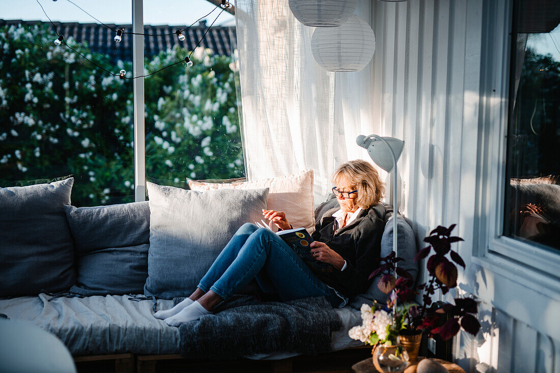 Frau sitzt auf dem Sofa im Wintergarten