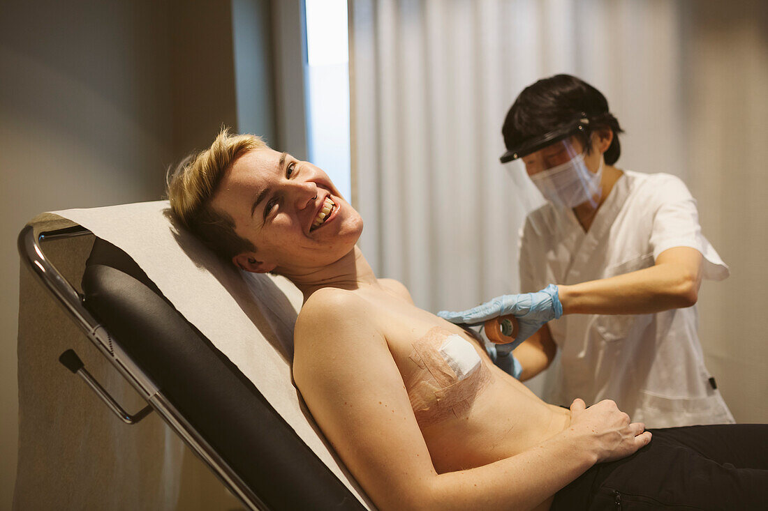 Patientin nach Mastektomie in der Arztpraxis liegend und lächelnd