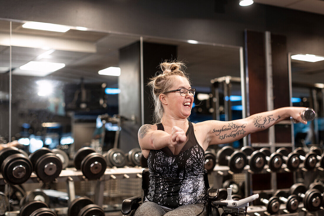 Happy woman on wheelchair training in gym