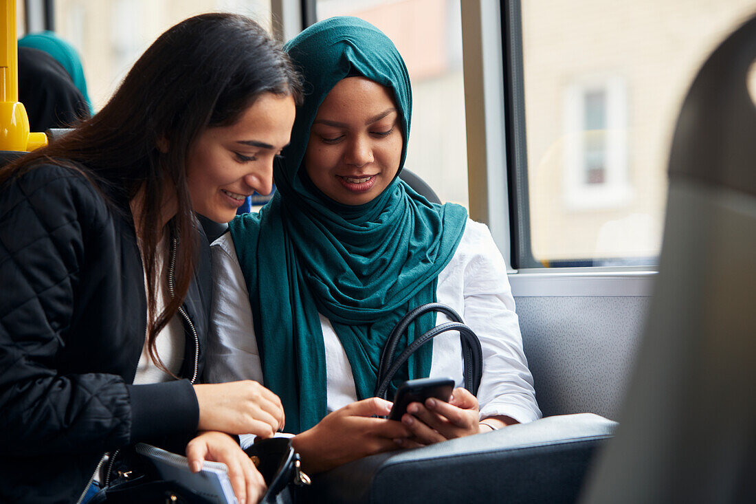 Freundin schaut im Bus auf ihr Handy