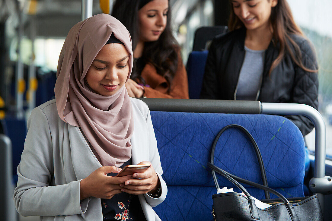 Junge Frau im Bus, die ein Mobiltelefon benutzt