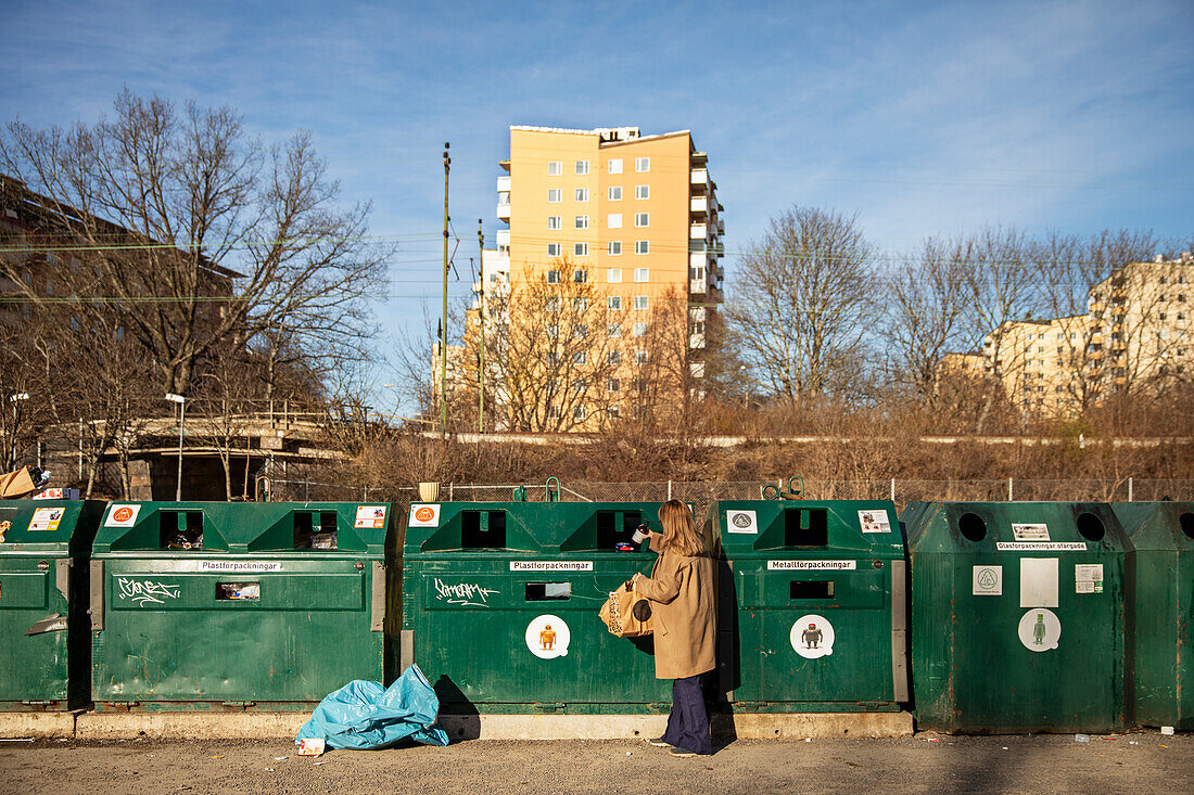 Frau wirft Müll in den Recycling-Behälter