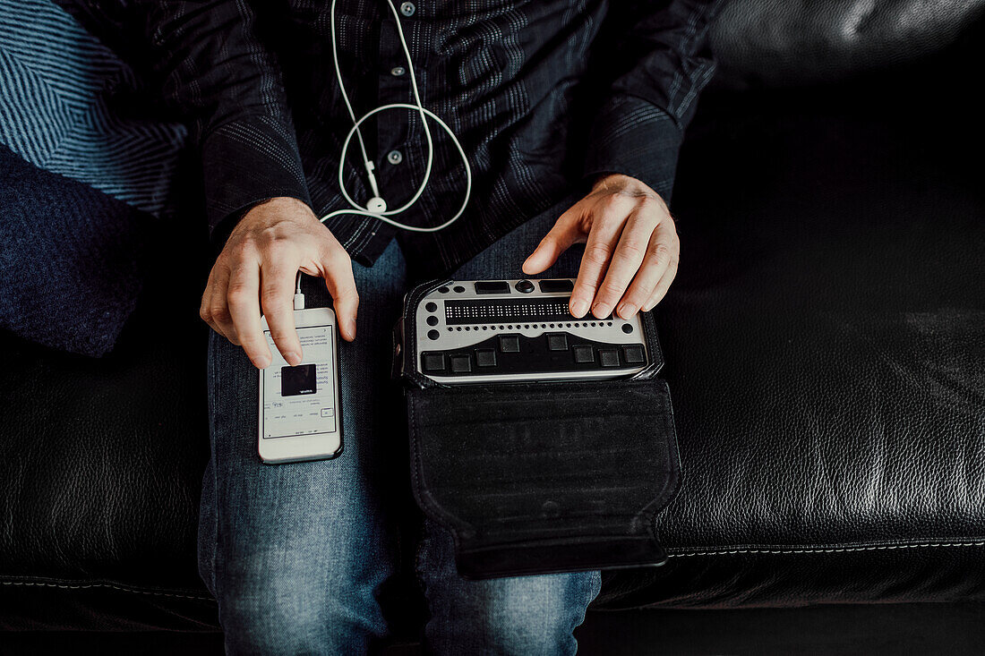 Man using Braille keyboard and smart phone