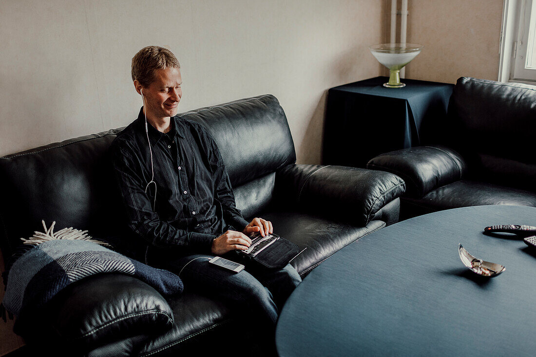 Man sitting on sofa and using Braille keyboard