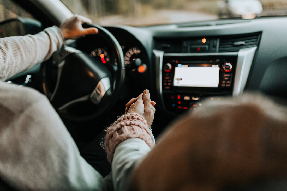 Couple in car holding hands
