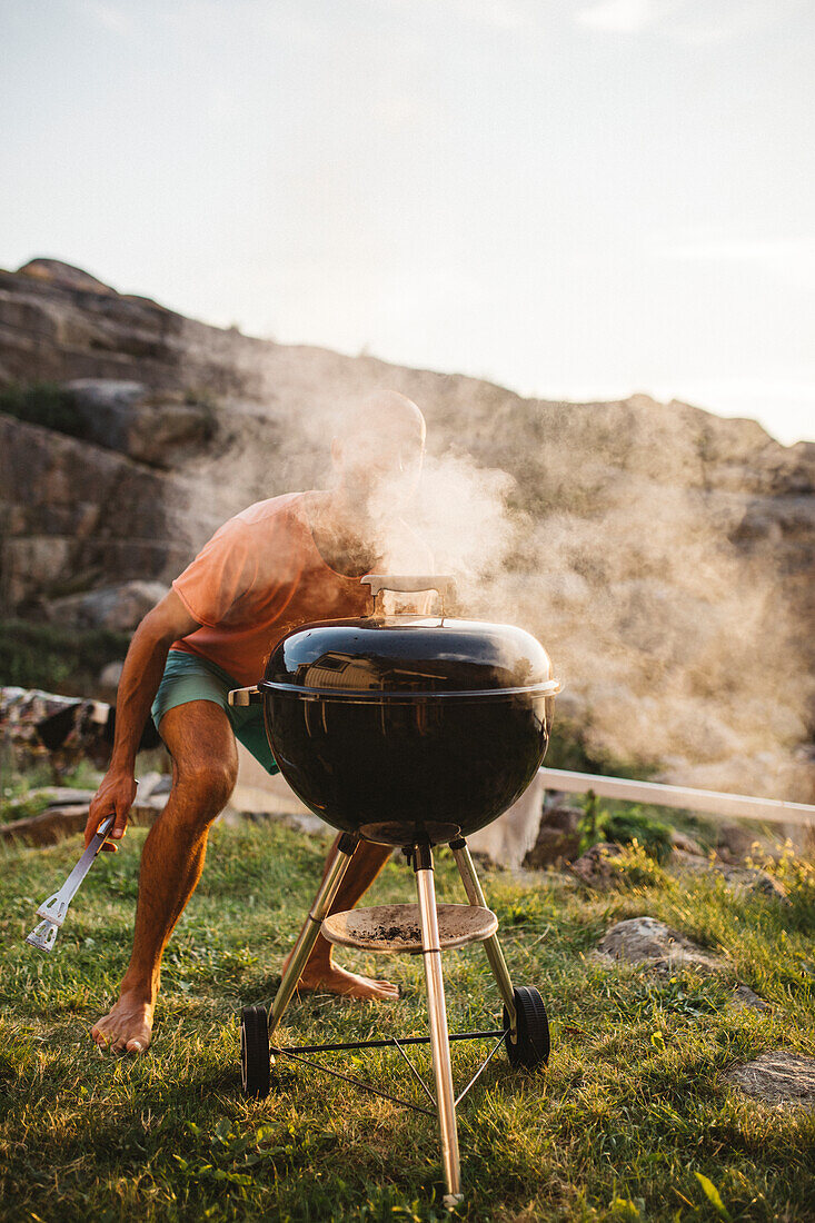 Mann beim Grillen im Garten