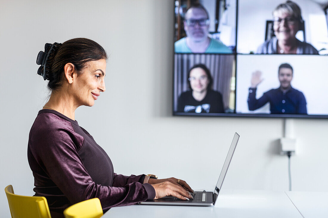 Frau im Sitzungssaal mit Videokonferenz