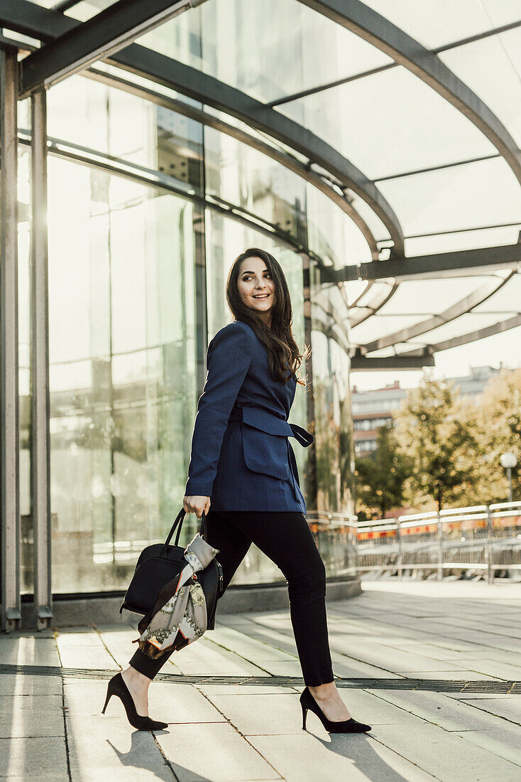 Geschäftsfrau im Gehen, Bürogebäude im Hintergrund