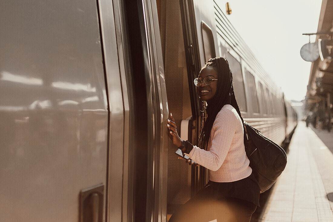 Lächelnde Frau beim Einsteigen in einen Zug