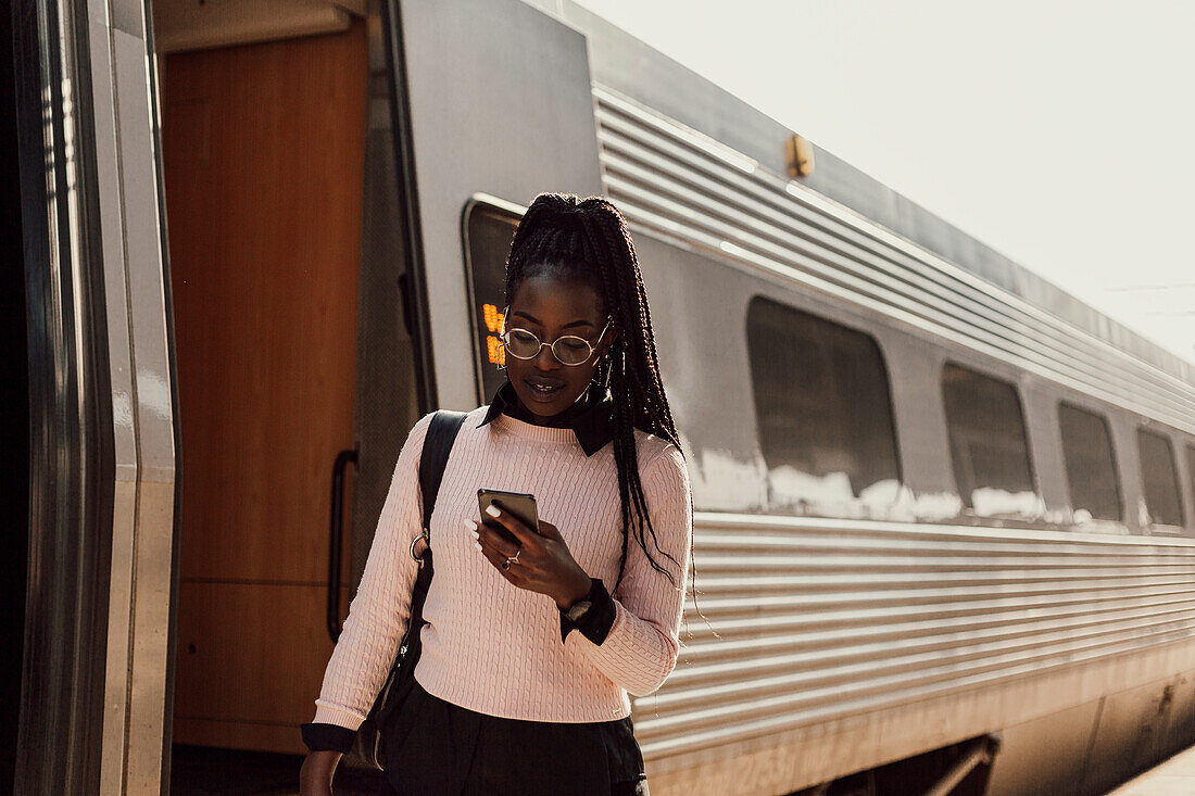 Young woman using phone at train station platform