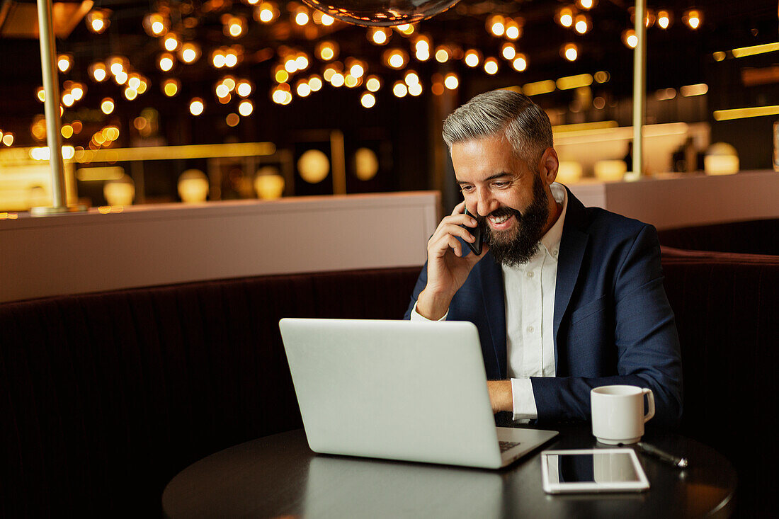 Geschäftsmann, der in einem Café mit einem Handy telefoniert