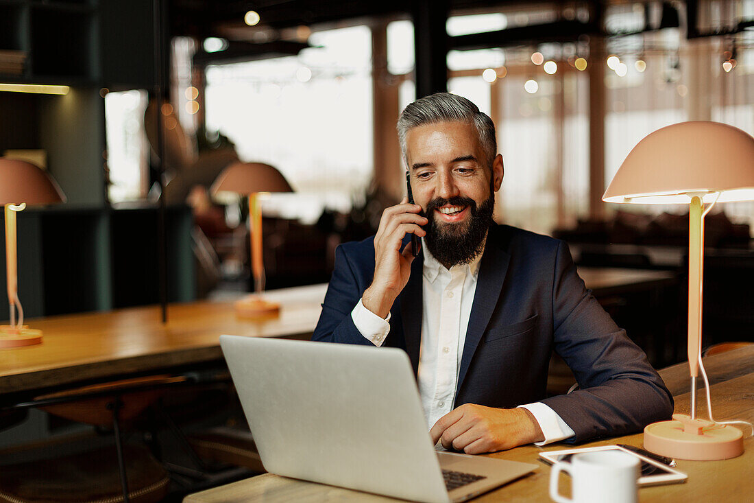 Businessman talking via cell phone in cafe