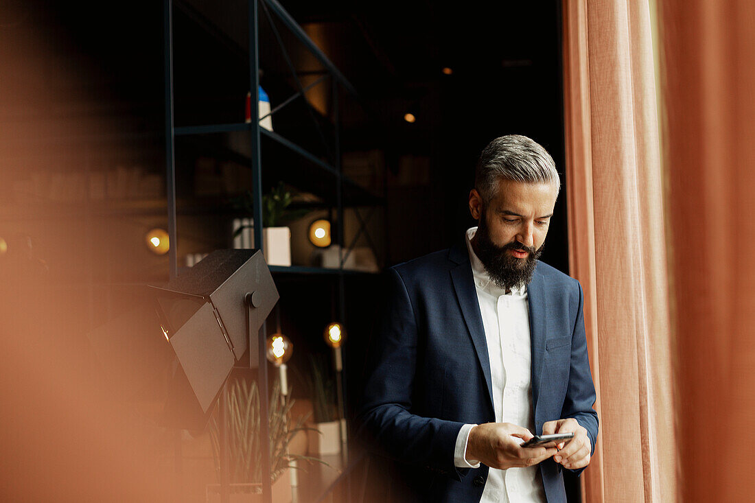 Businessman using cell phone in cafe