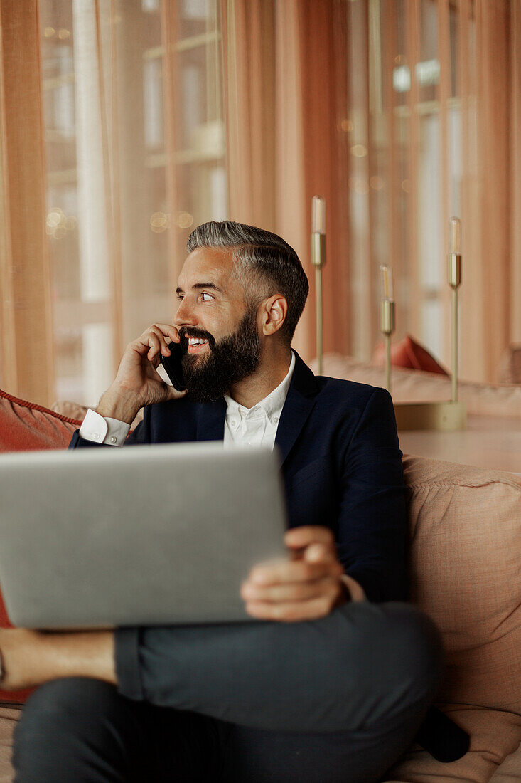 Businessman talking via cell phone in cafe