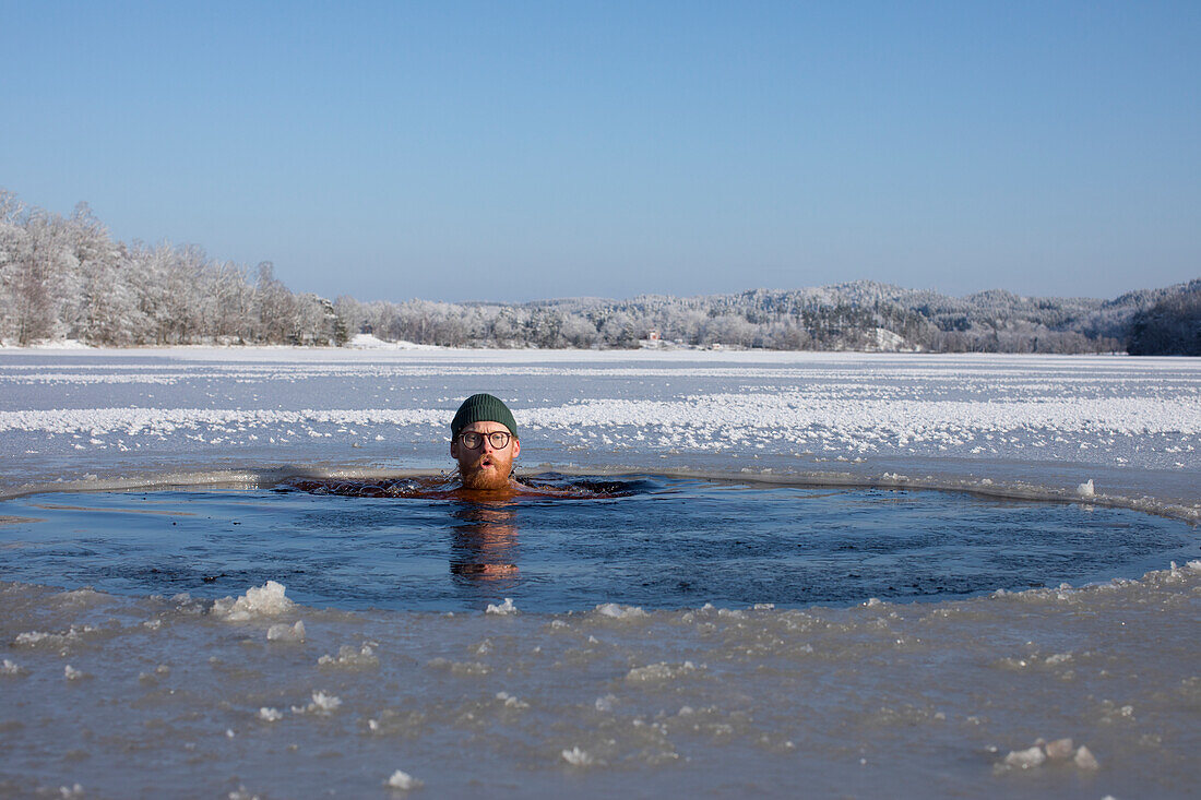 Man swimming in frozen lake