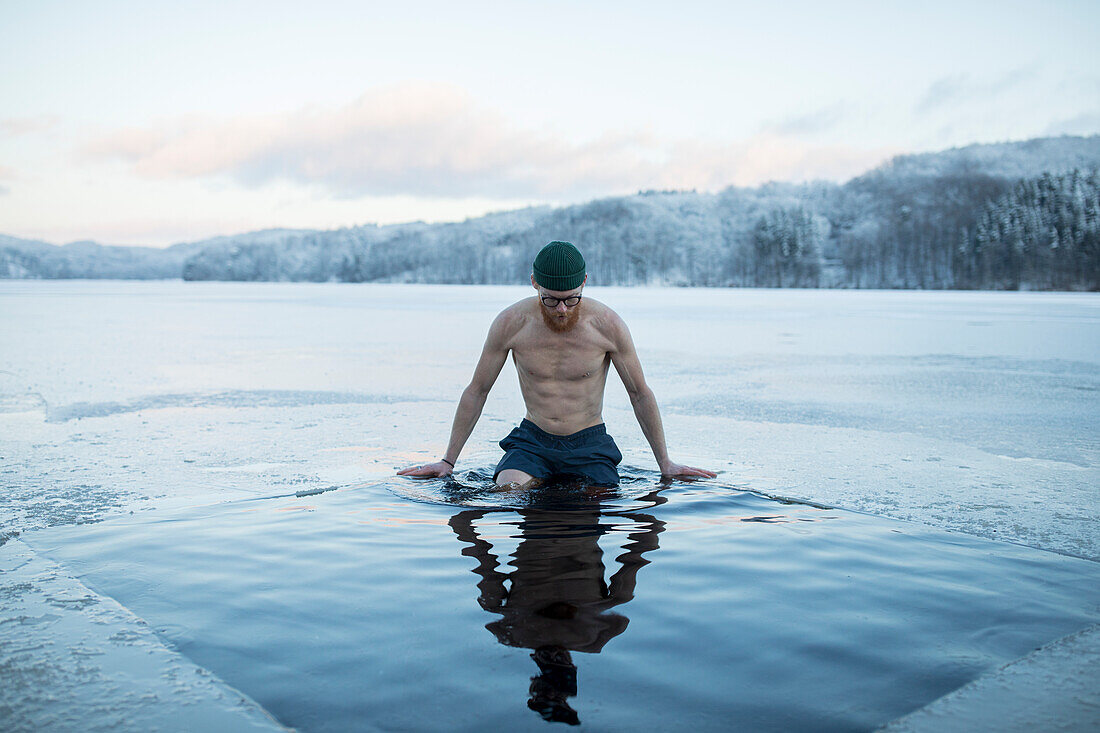 Man swimming in frozen lake