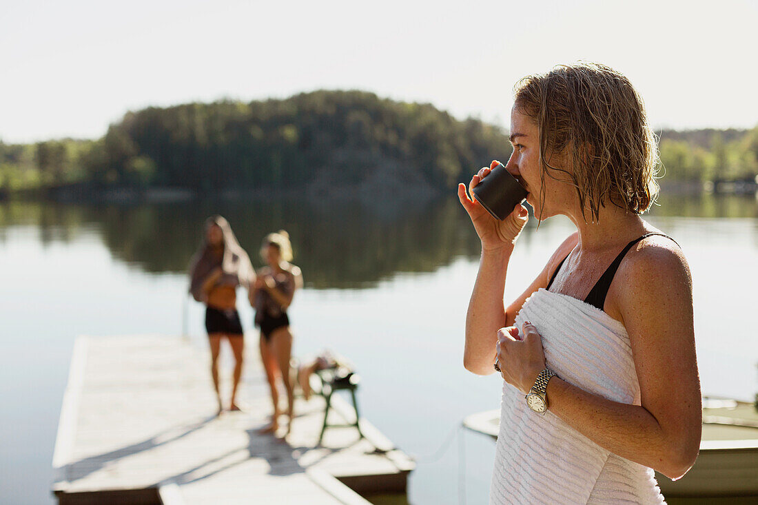 Woman drinking from mug at lake