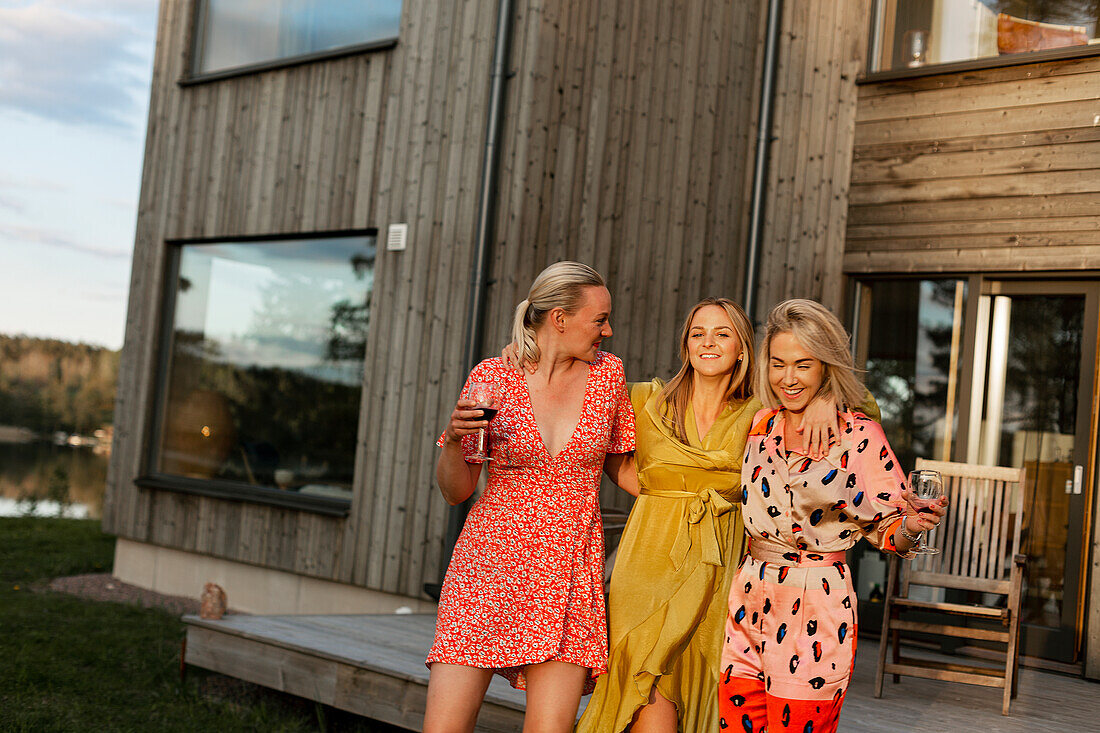 Smiling female friends holding wine glasses in backyard