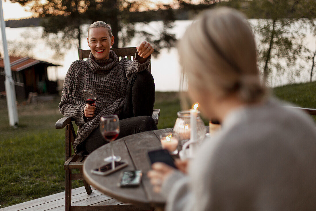 Female friends sitting on porch and drinking wine