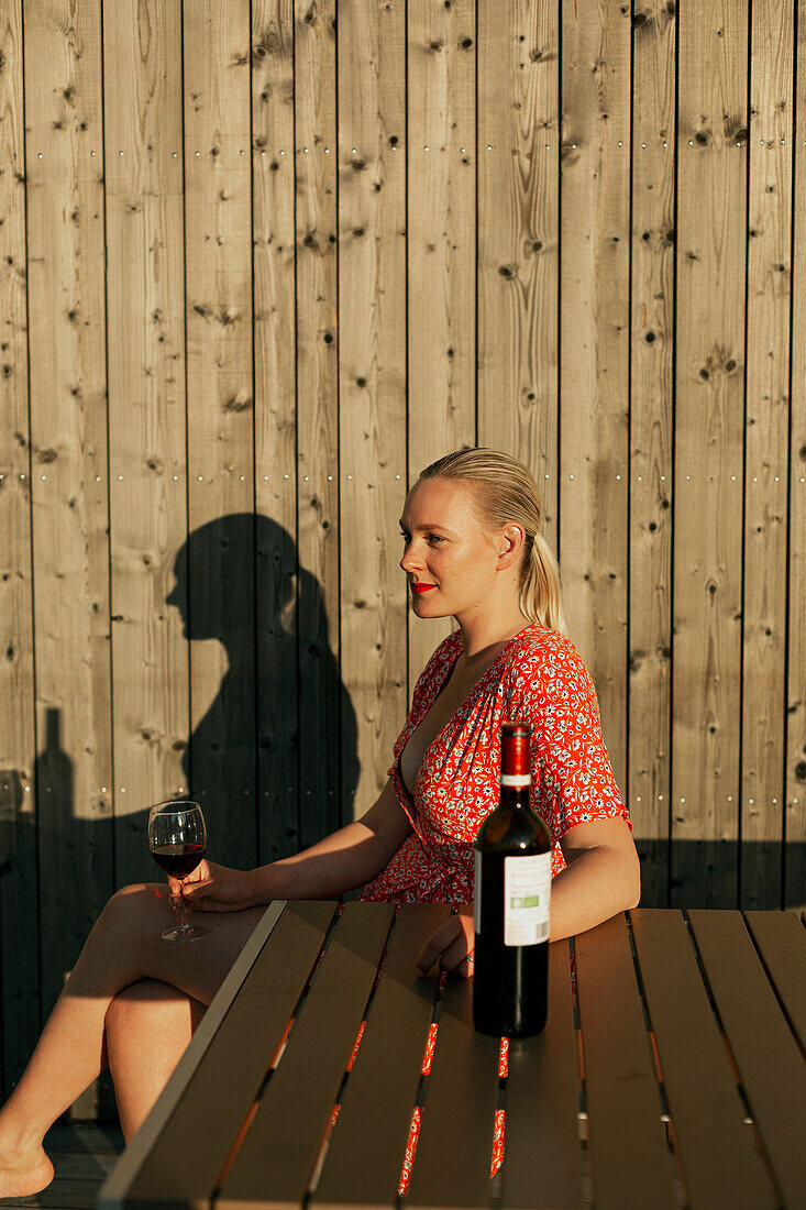 Frau trinkt Rotwein auf Veranda