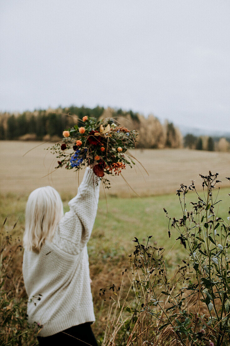 Frau hält großen Blumenstrauß in die Höhe