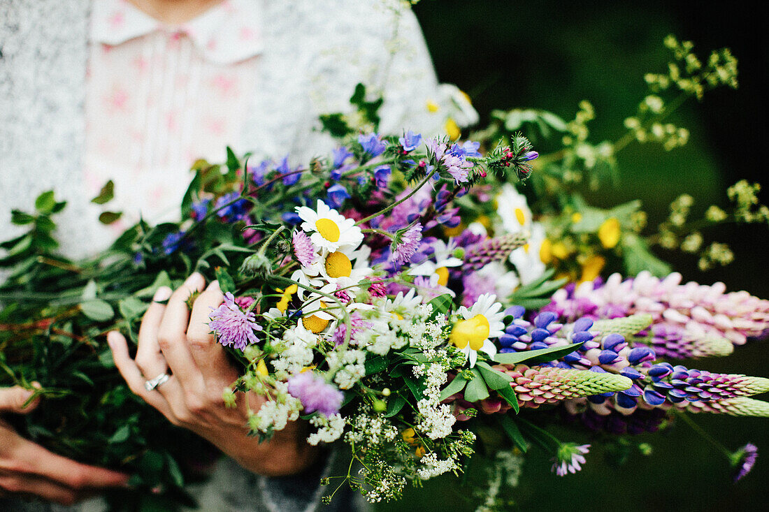 Hände halten einen Strauß Wildblumen