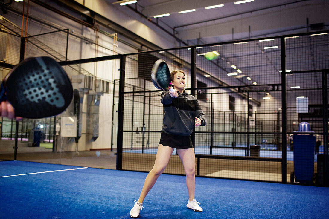 Woman playing padel at indoor court