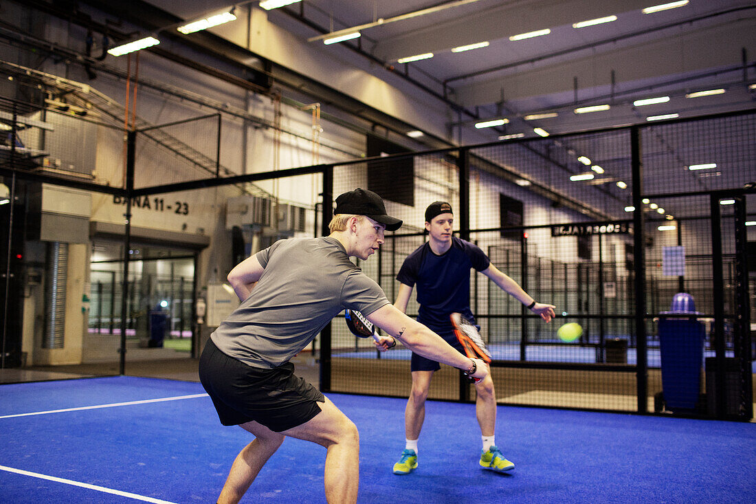 Men playing doubles padel at indoor court