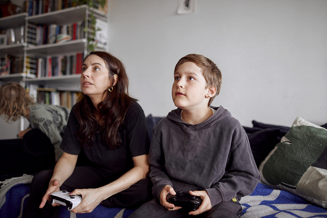 Mutter mit Sohn auf dem Sofa sitzend und Videospiele spielend