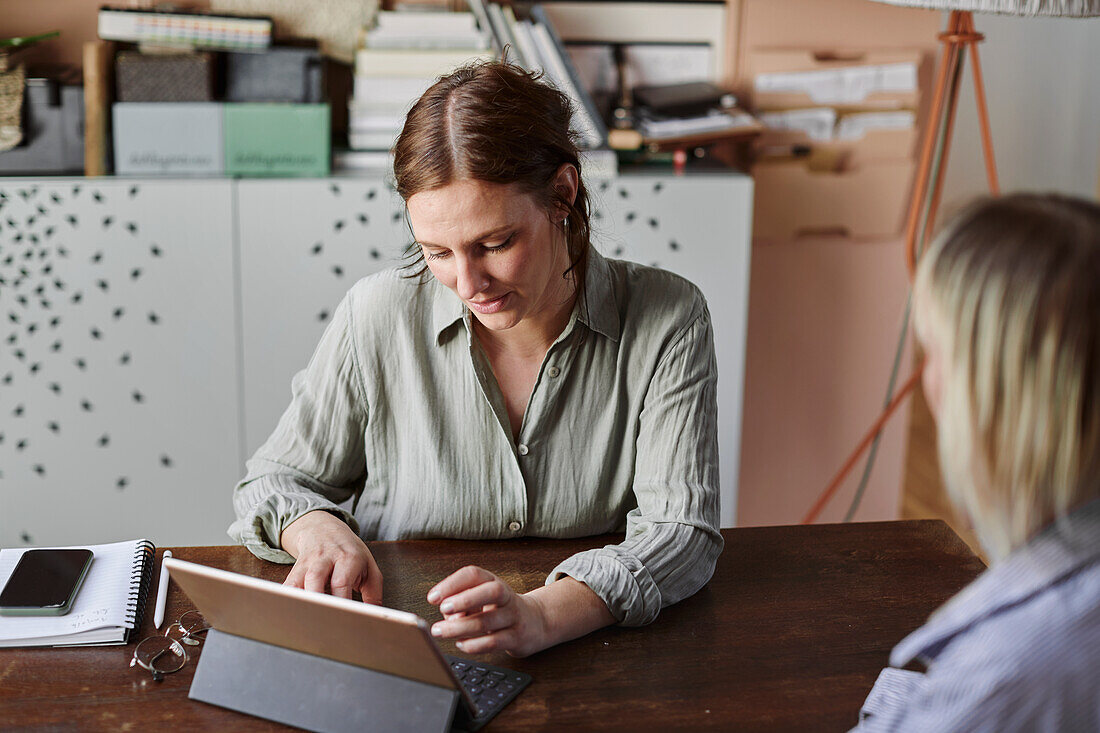 Women sitting at desk and using tablet