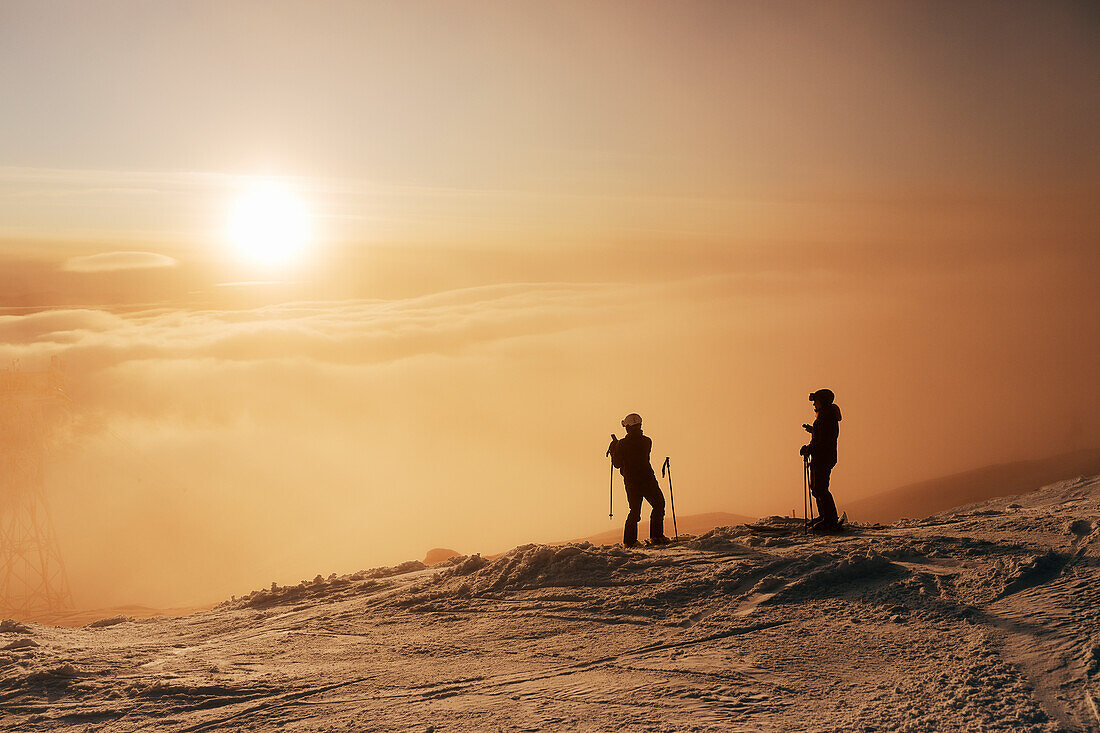 Skifahrer auf verschneiter Piste mit Blick auf den Sonnenuntergang