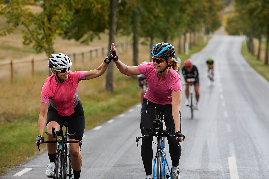 Smiling female cyclist giving each other high five