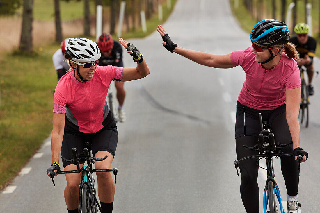 Happy cyclists giving each other high five