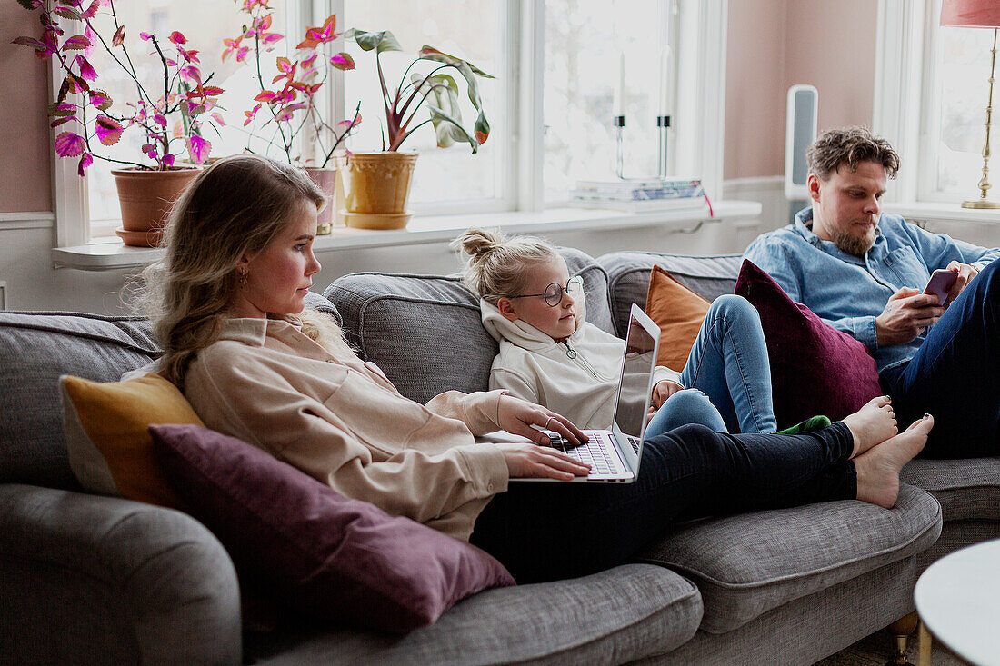 Parents with daughter sitting on sofa