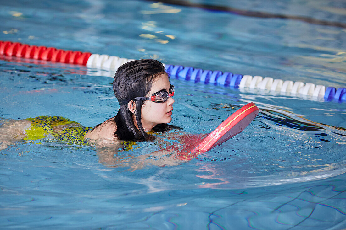 Girl learning to swim in indoor swimming pool