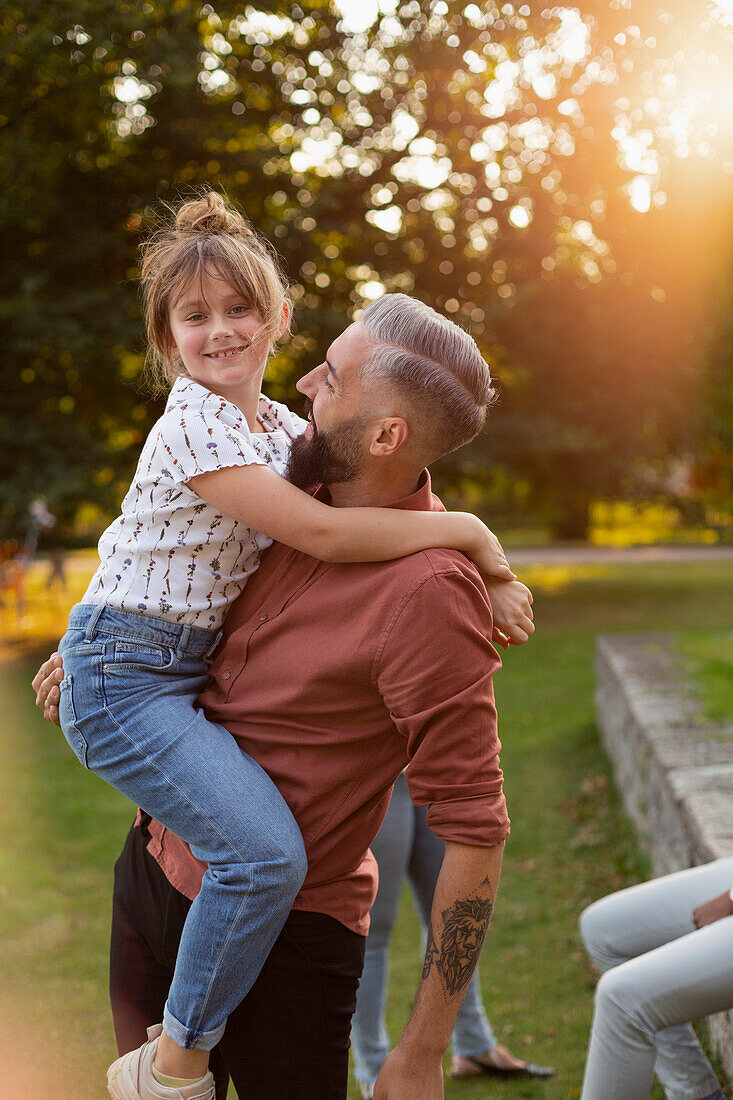 Father carrying daughter in park