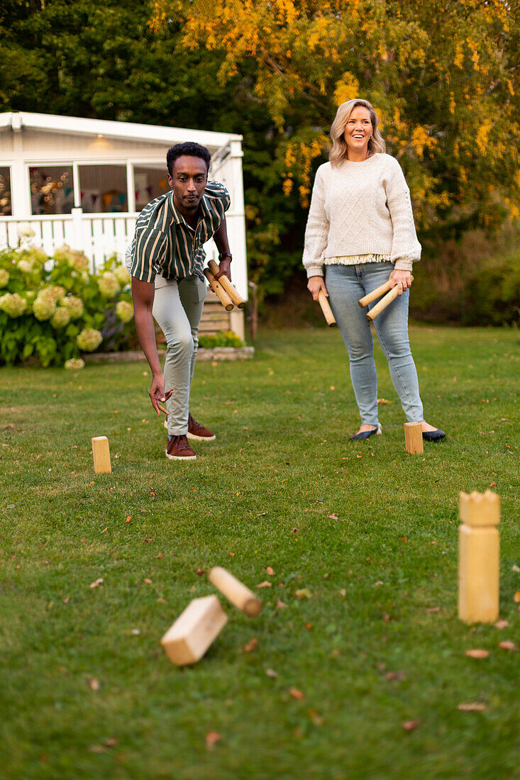 Man and woman playing molkky game in park