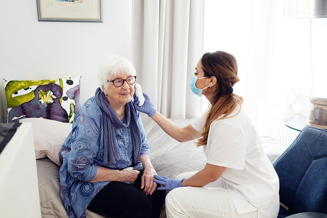 Krankenschwester prüft die Temperatur einer Frau zu Hause