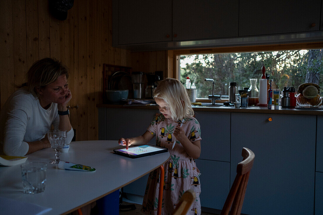 Mädchen, das ein digitales Tablet benutzt, während die Mutter zusieht