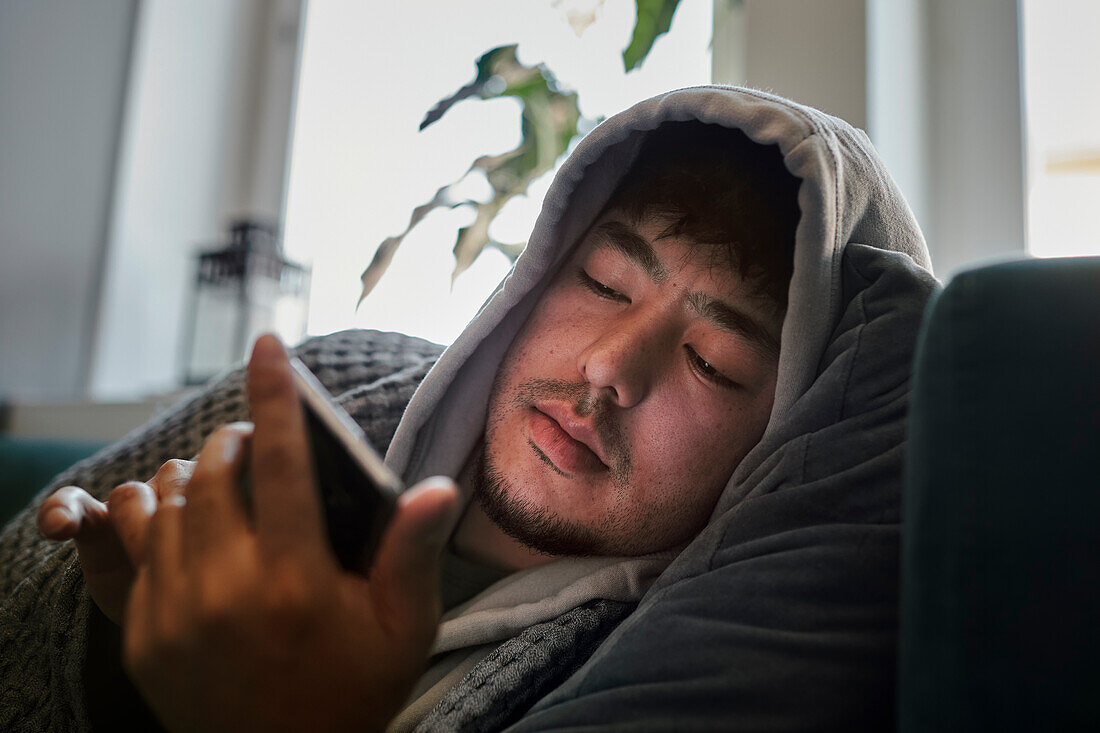 Ill man on sofa using cell phone
