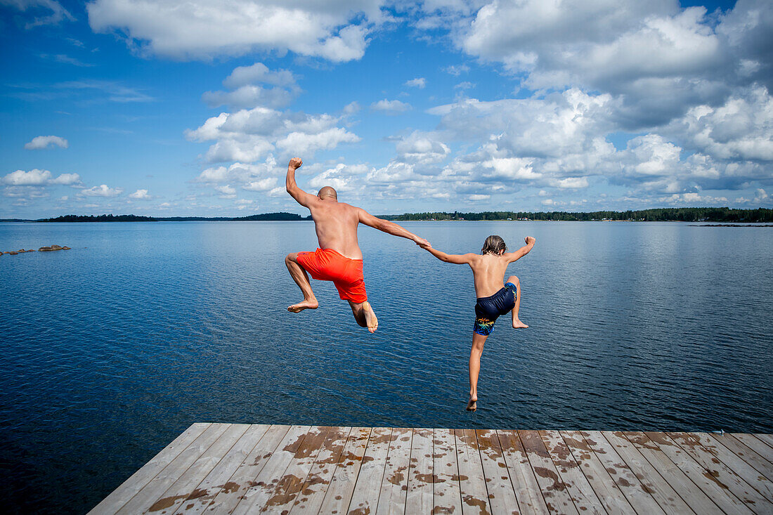 Father and son jumping into sea