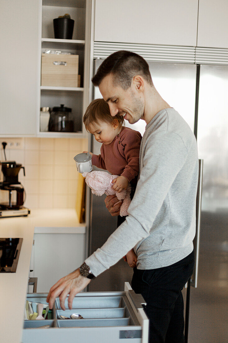 Vater trägt kleines Mädchen in der Küche